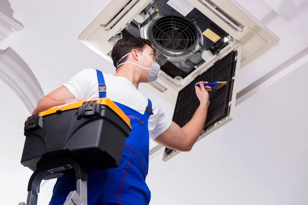 Technician servicing a ceiling-mounted commercial air-conditioning cassette