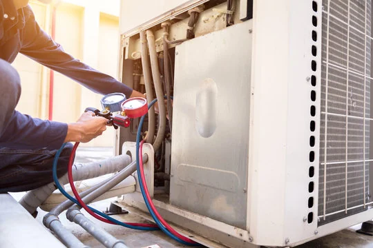 Technician checking an outdoor heat pump using pressure gauges